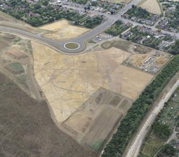 Aerial view of the archaeological investigations on Clay Farm, to the east of Shelford Road, with the new Addenbrooke's Road, July-August 2010. Looking across the site from north east at bottom to south west at top. Oxford Archaeology East.